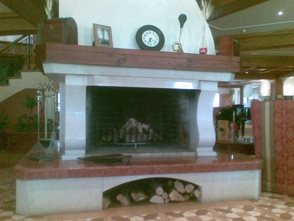 Камина с открито огнище в хотелско фоайе.Облицовка от варовик и мрамор Росо Верона.